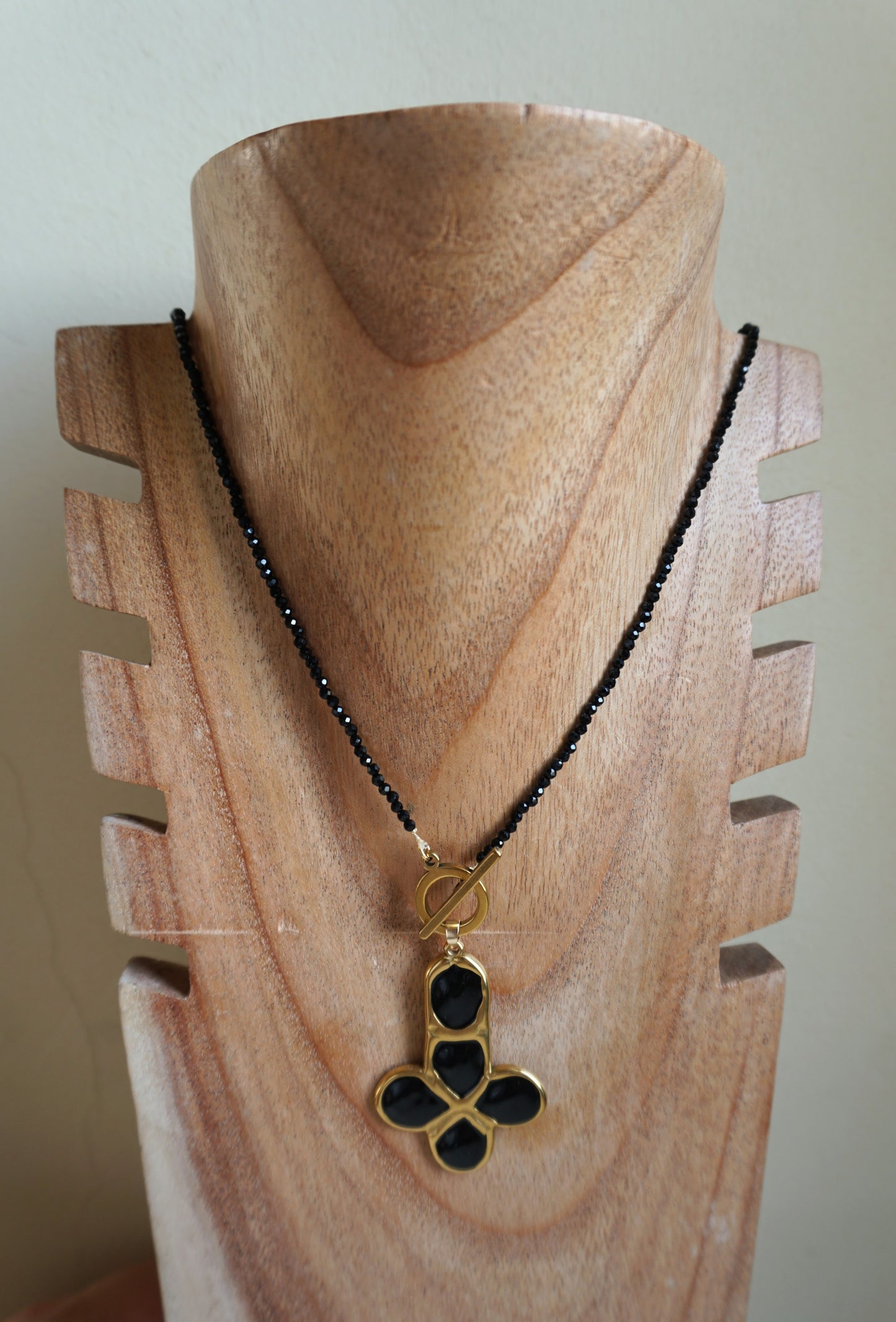 Tira larga de piedras y cruz dorada de piedras negras