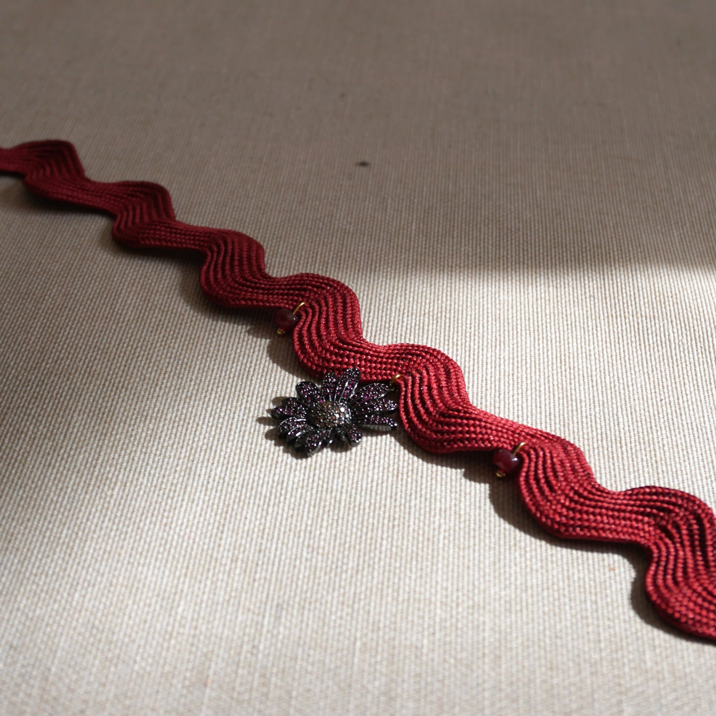 Girocollo ondulato bordeaux con fiore